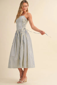 A woman wearing a blue and white striped midi dress with side tie detail and corset-style front lacing