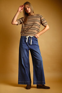 A woman wearing a brown and cream stripe pattern short sleeve knit top with a white drawstring waistband