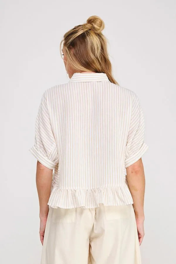 A woman wears a cream button down striped ruffle detail top from shop daisy womens boho chic clothing collection