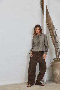 A woman wears a gray plaid bow tied collar shirt made of soft fabric featuring a stylish tied collar design
