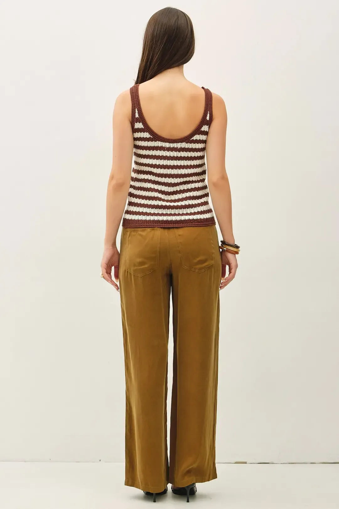 A woman wears a maroon and cream knitted textured stripe tank sweater with rounded neckline and ribbed trim