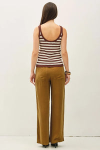 A woman wears a maroon and cream knitted textured stripe tank sweater with rounded neckline and ribbed trim