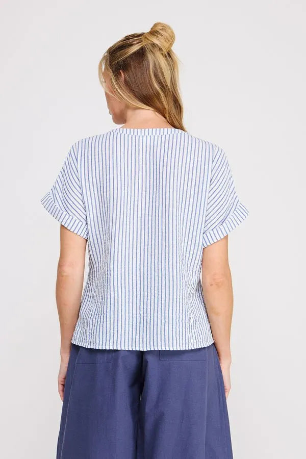 A woman wears a light blue and white striped button down front tie detail v neck top from shop daisy womens boho clothes