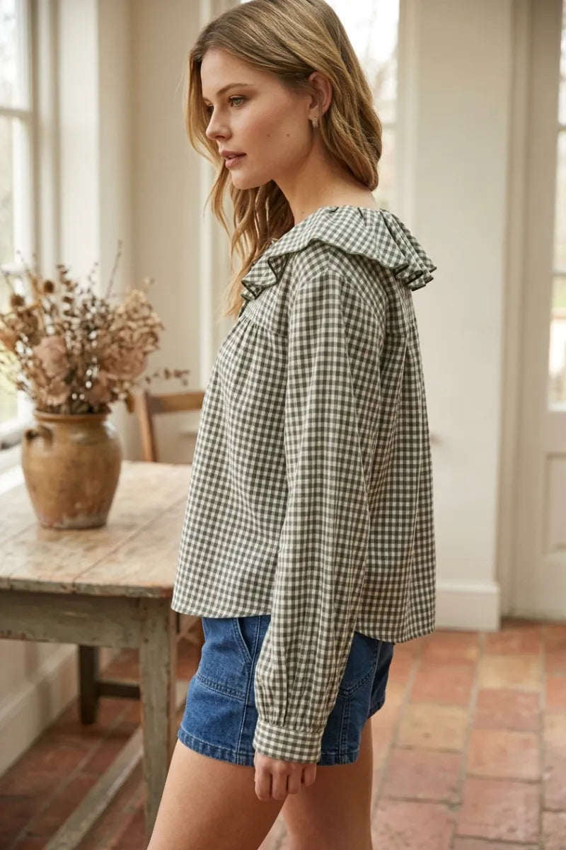 A woman wearing a long-sleeved mini gingham ruffled collar blouse with green and white gingham pattern