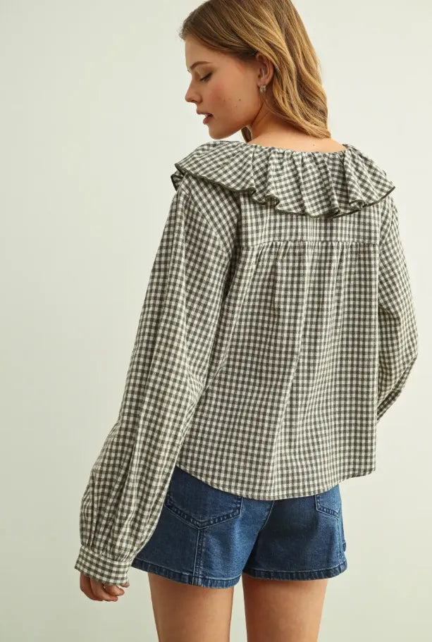 A woman wears a black and white mini gingham ruffled collar blouse with long sleeves and an off the shoulder design