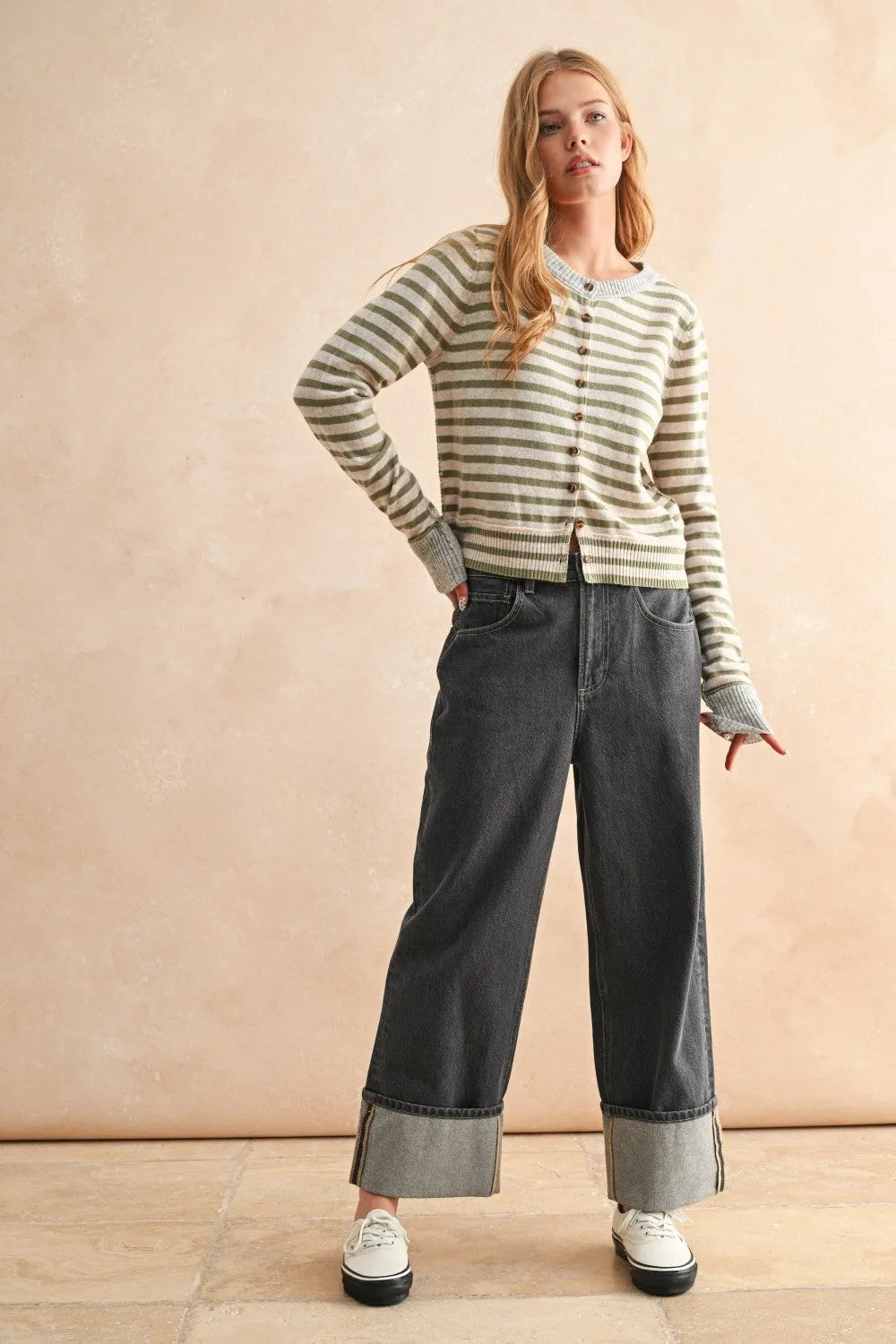 A woman wears a muted green and off-white striped pattern button front cardigan with long sleeves