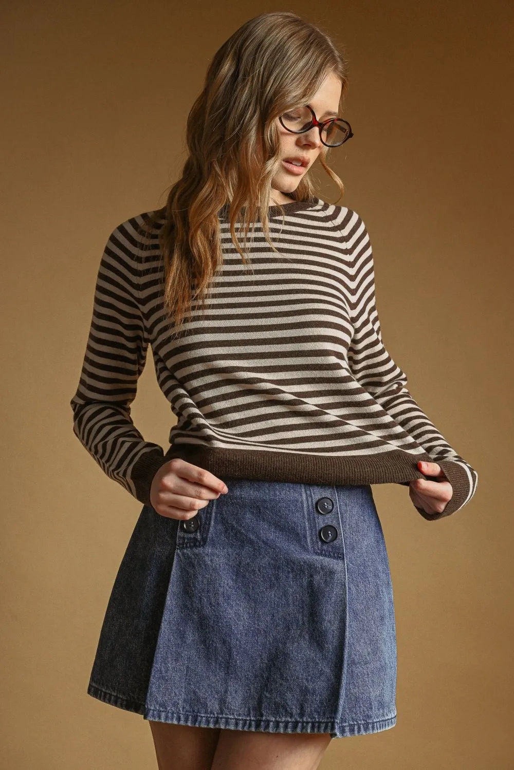 A woman wears a black and beige striped round neck sweater with ribbed cuffs and hem in a long-sleeved style