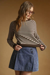 A woman wears a black and beige striped round neck sweater with ribbed cuffs and hem in a long-sleeved style