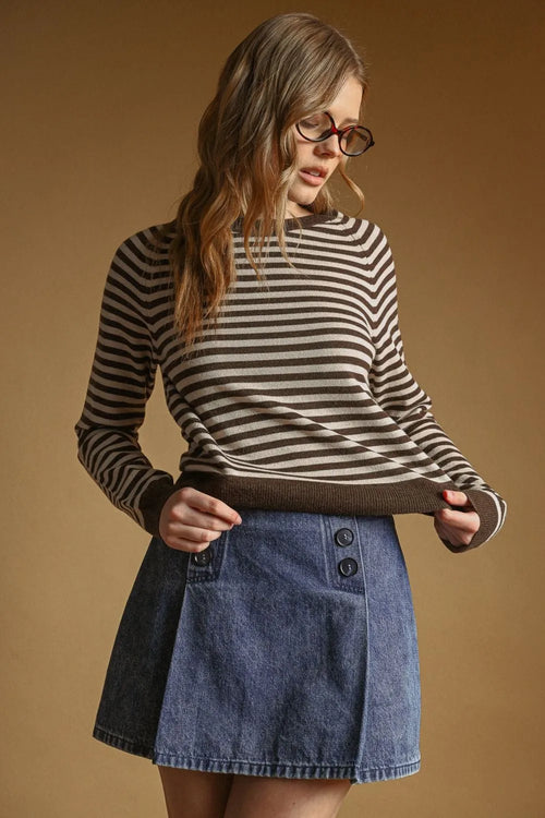 A woman wears a black and beige striped round neck sweater with ribbed cuffs and hem in a long-sleeved style