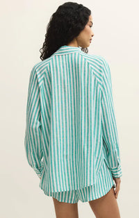 A woman wearing the perfect linen striped top in teal and white vertical stripes with long sleeves and button-up design