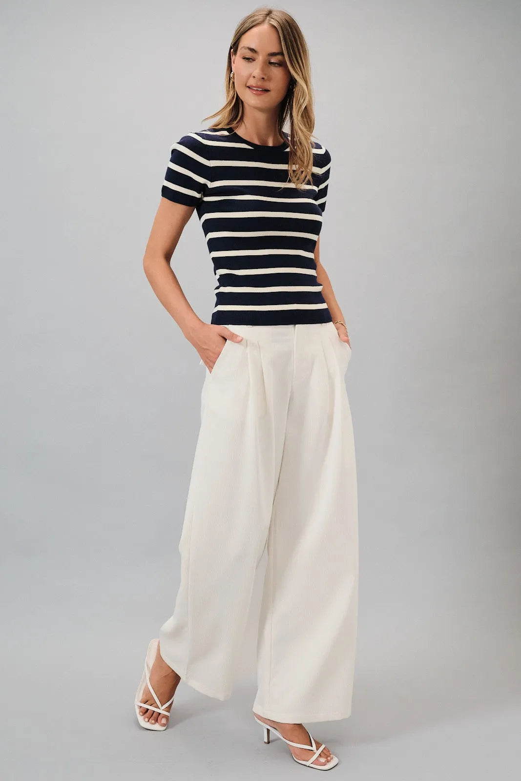 A woman wears a navy and white striped round neck short sleeve top paired with white wide-leg trousers