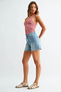 Woman in mid rise walking denim shorts with slit and gingham halter top
