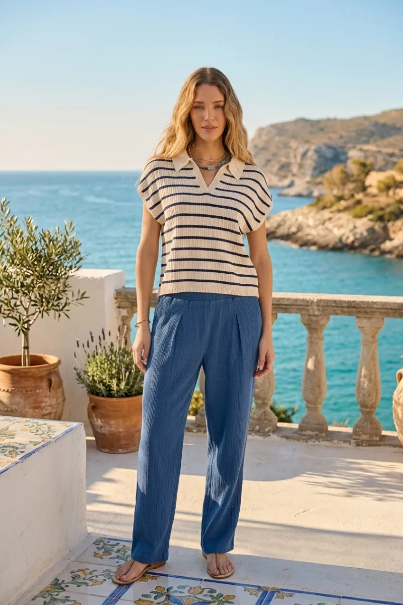 A woman wears a supply poet short-sleeved polo shirt with black and cream stripes and a collared v-neckline in relaxed fit