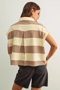 A woman wears a wide striped short sleeve polo shirt in beige and brown tones with a cropped fit