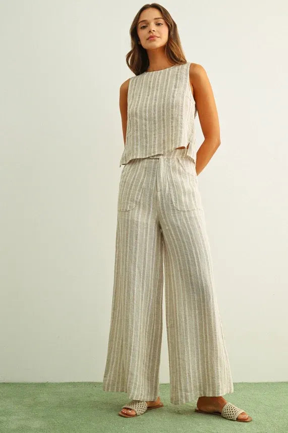 A woman wearing a soft beige jacquard linen twisted tie back top with matching wide-leg linen trousers