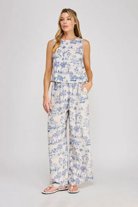 A woman wears a back open printed top in blue and white toile pattern from shop daisy womens boho clothes