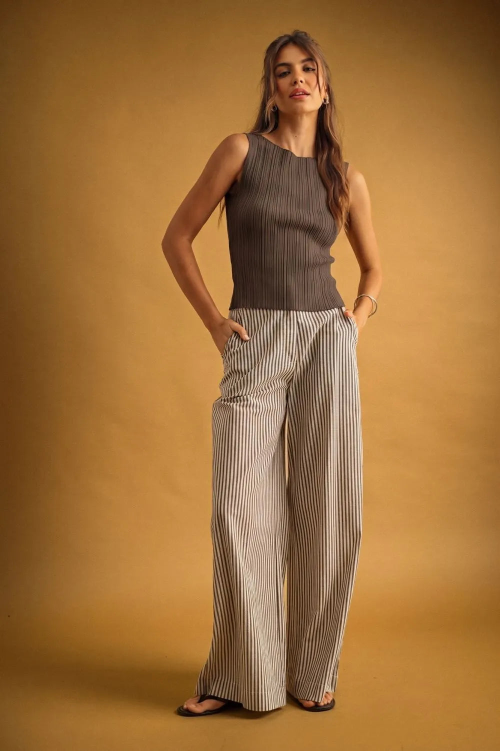 A woman wearing a viscose ribbed knitted sleeveless charcoal gray top styled with boho chic clothing trousers