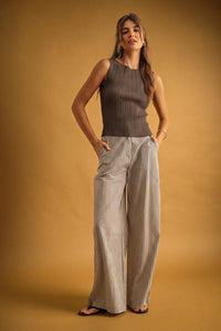 A woman wearing a viscose ribbed knitted sleeveless charcoal gray top styled with boho chic clothing trousers