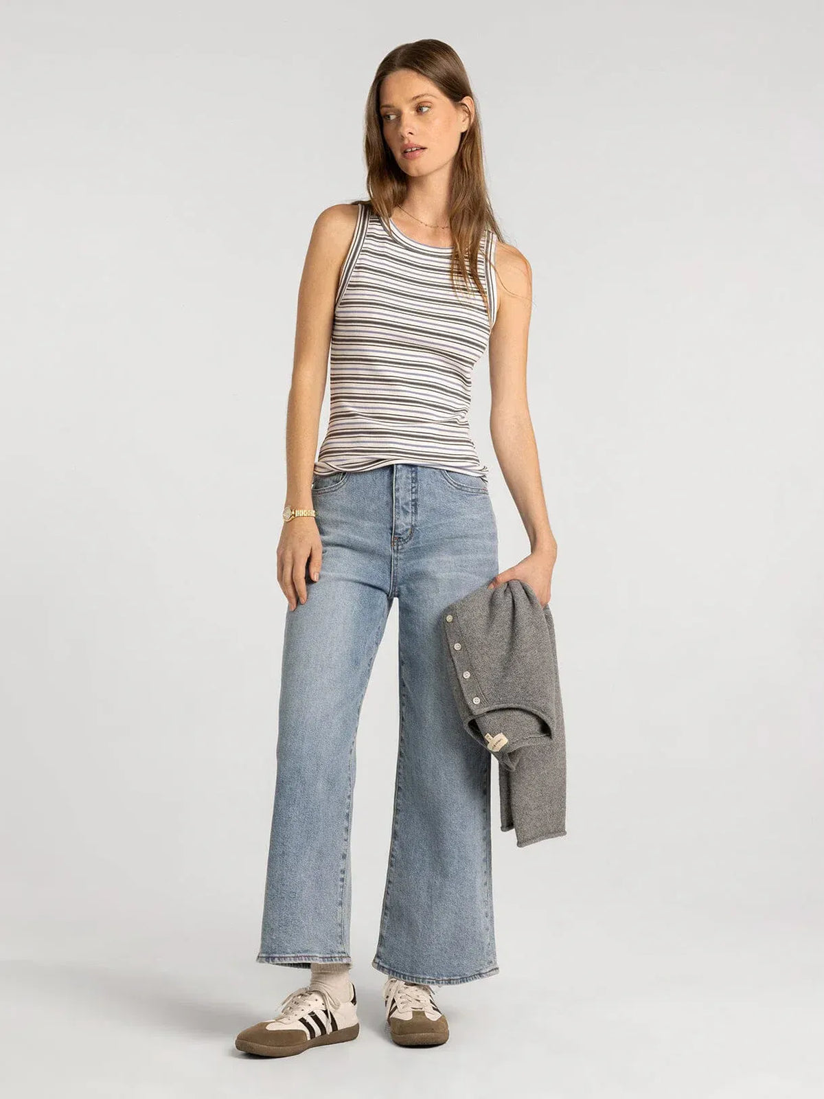 A woman wears a sleeveless black and white striped edlin basic tank designed for casual wear by Thread and Supply