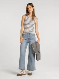 A woman wears a sleeveless black and white striped edlin basic tank designed for casual wear by Thread and Supply