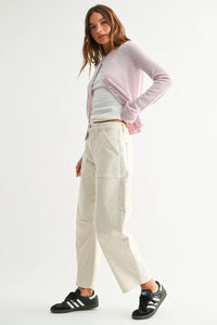 Woman in lavender cardigan, white crop top, and utility seamed barrel jeans