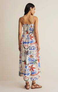A woman wears the cornelia getaway maxi dress featuring a vibrant tropical print in bold reds blues and greens