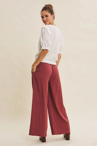 A woman wears white ribbed blouse and maroon step washed wide leg pants for a stylish casual look