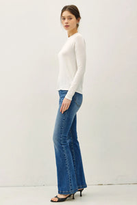 A woman wears a white modal raglan sleeve layering basic top paired with blue flared jeans and black heels