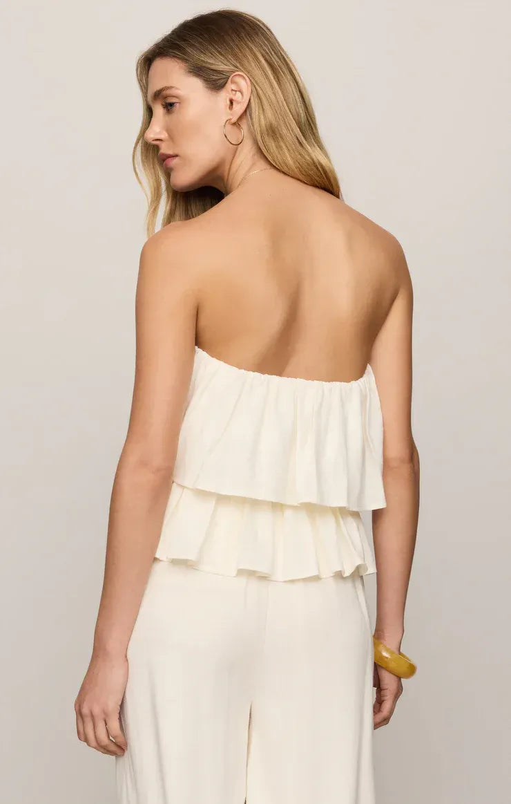 A woman wears a white strapless linen mabel top with layered ruffles and matching wide-leg pants