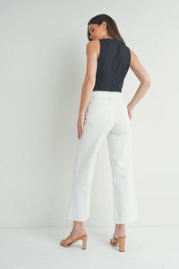 Woman wearing black sleeveless top and white slim wide leg jeans with scissor cut hem