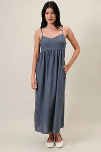 A denim-blue women’s midi slip dress with sweet heart neck spaghetti straps and a gathered waist detail