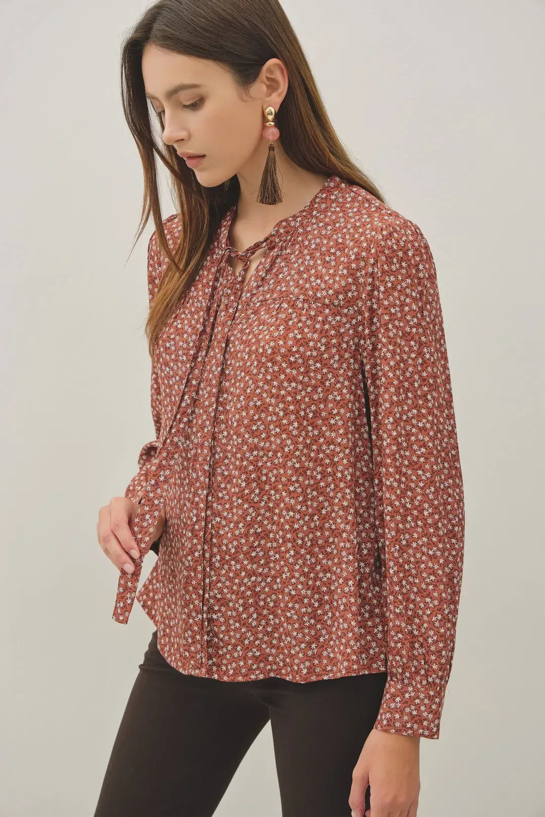 A rust-colored ditsy printed tie front collar blouse with long sleeves and matching tied cuffs in lightweight fabric