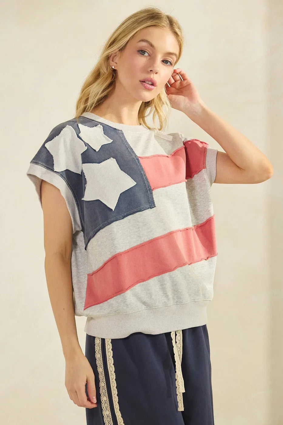 A women’s short-sleeved mineral wash top with american flag patch design in navy blue white and coral pink stripes
