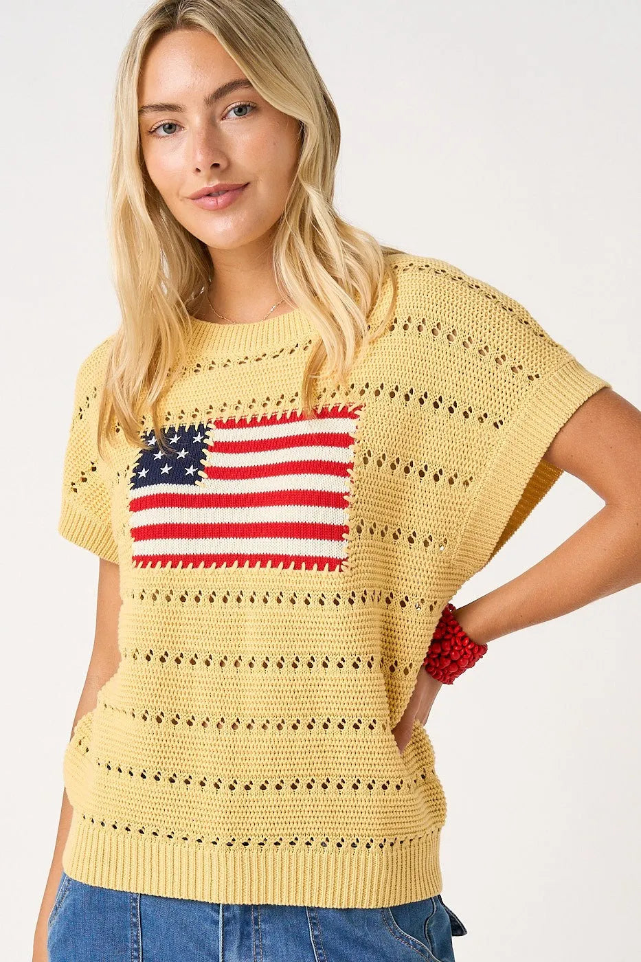 Yellow crocheted knit sweater top with a red white and blue american flag patch on the chest
