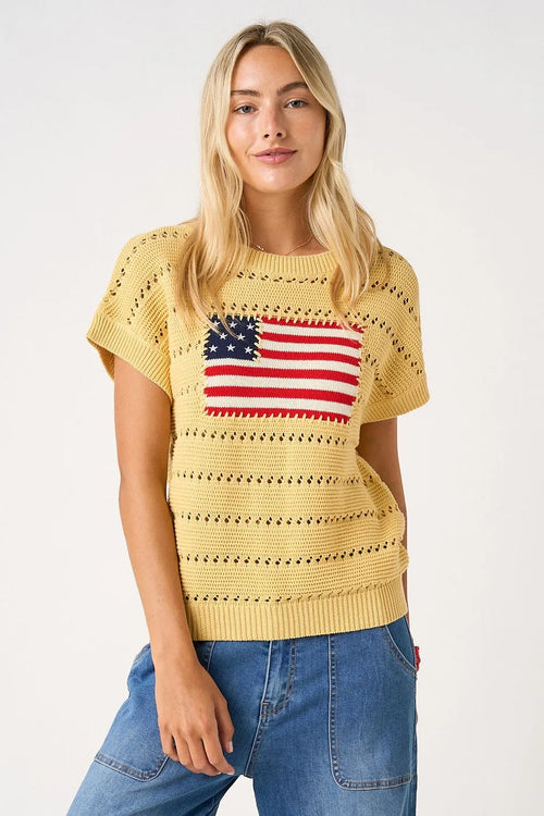 Yellow knitted sweater top featuring an american flag patch in red white and blue on the chest