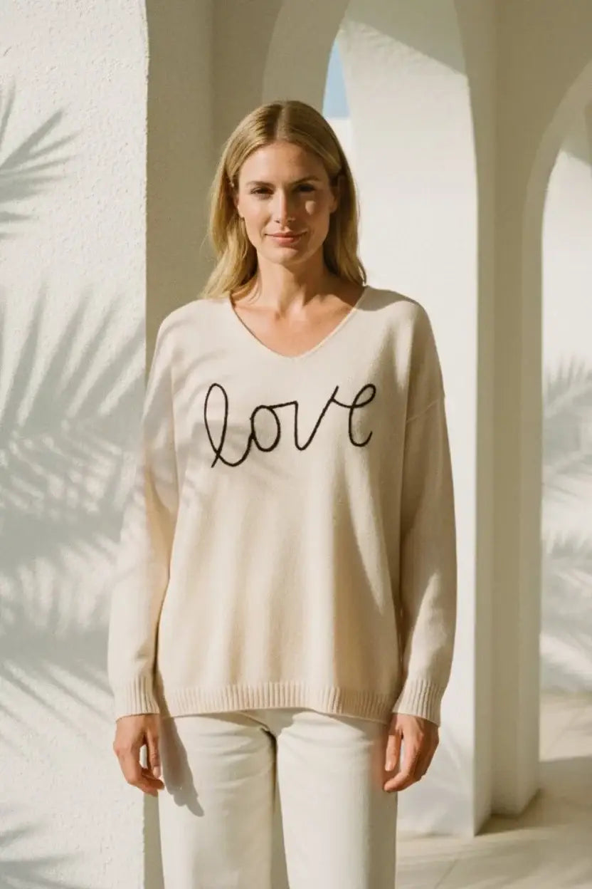 Cream-colored knit sweater with cursive love embroidery for perfect Valentines Day