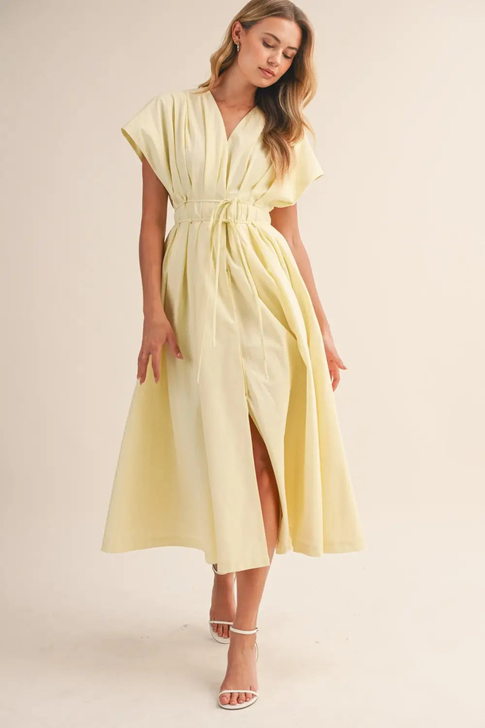 a flowing pale yellow poplin belted maxi dress with v-neckline short draped sleeves and cinched waist belt