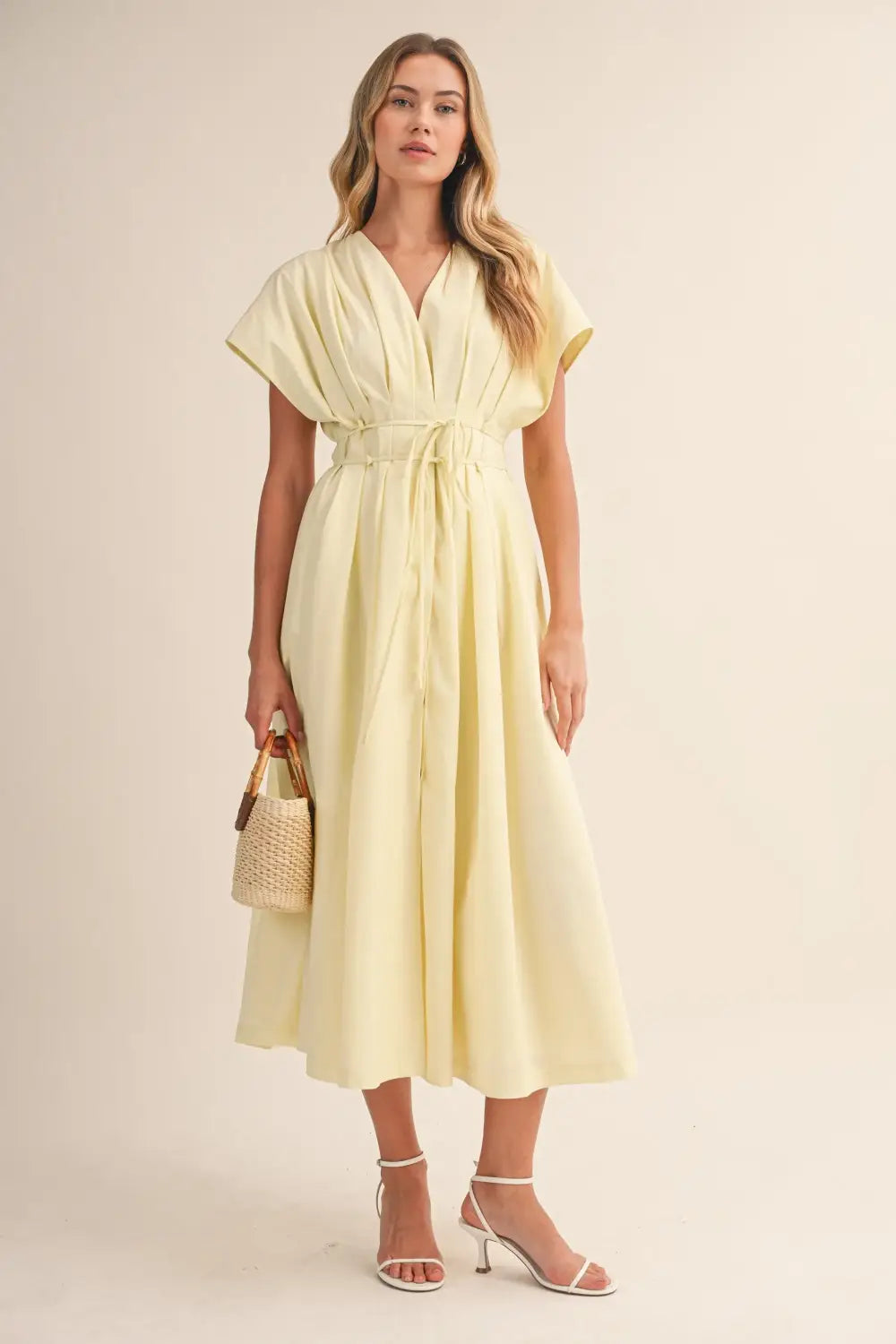 a flowing pale yellow poplin belted maxi dress with v-neckline short draped sleeves and cinched waist belt