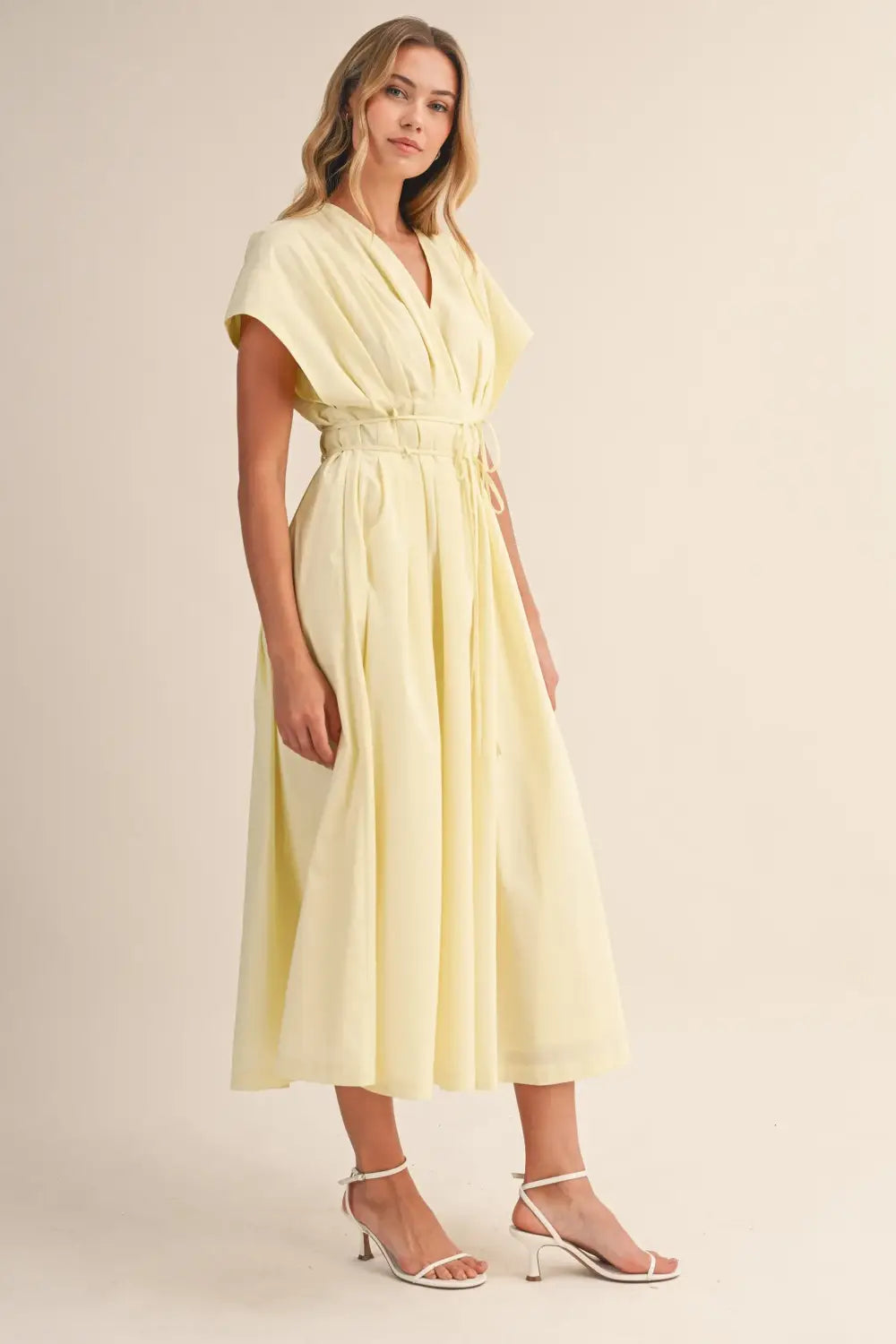 a flowing pale yellow poplin belted maxi dress with v-neckline short draped sleeves and cinched waist belt