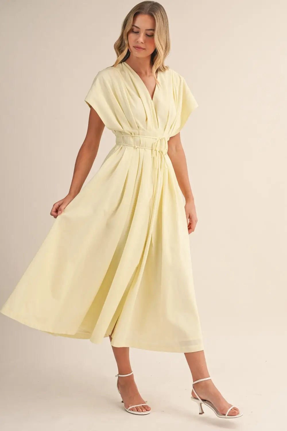a flowing pale yellow poplin belted maxi dress with v-neckline short draped sleeves and cinched waist belt
