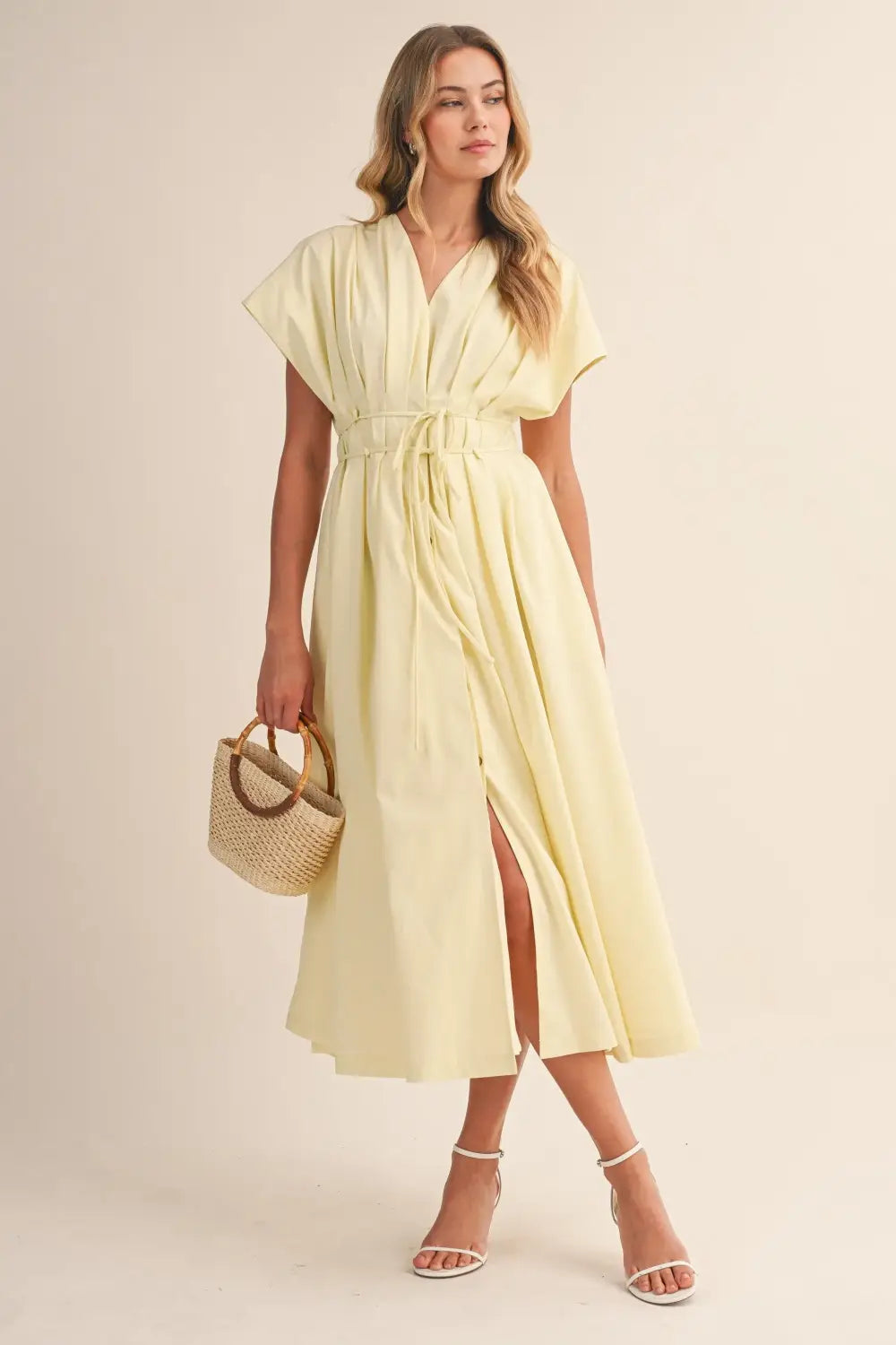 a flowing pale yellow poplin belted maxi dress with v-neckline short draped sleeves and cinched waist belt