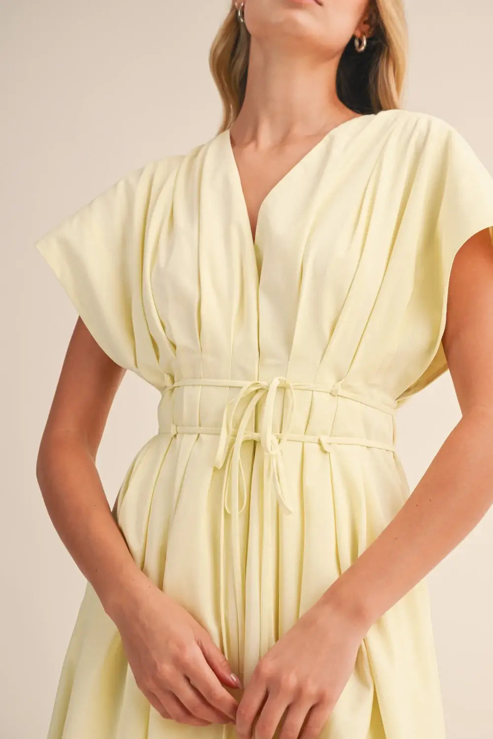 a flowing pale yellow poplin belted maxi dress with v-neckline short draped sleeves and cinched waist belt