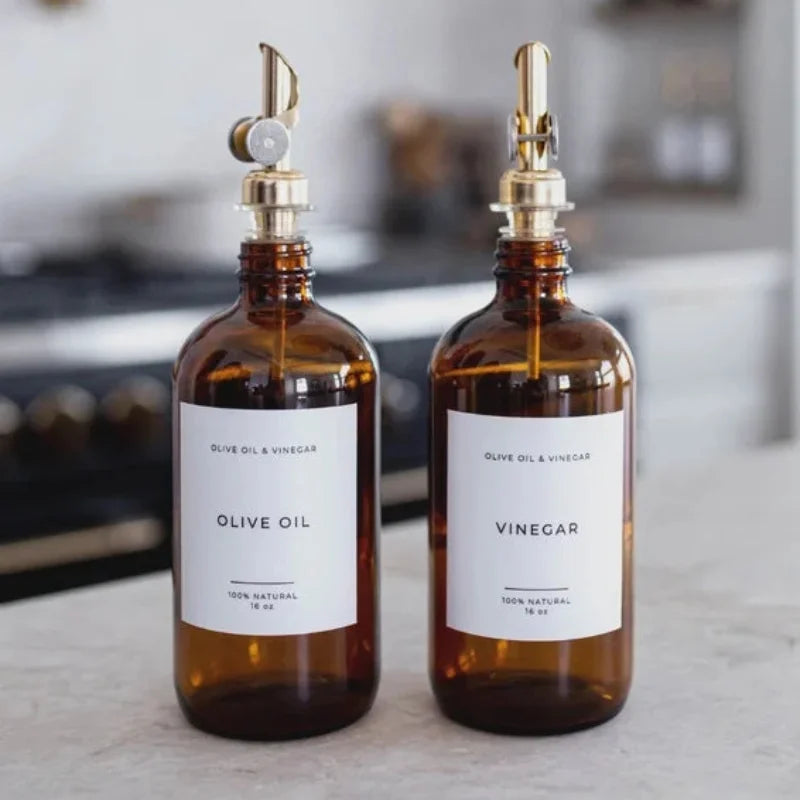 Amber glass dispenser bottle for olive oil with brass spout and white label