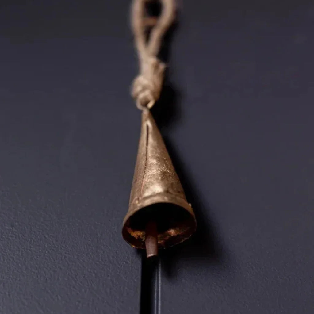 Tapered brass bell ornament with antique gold finish, rope hanger, and metal clapper