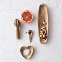 Arrangement of mango wood heart shaped dish with kitchen utensils and grapefruit on white surface