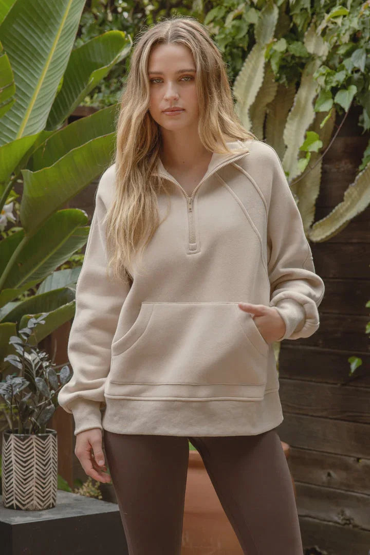 Beige half zip long sleeve knit top featuring a front pocket for stylish comfort