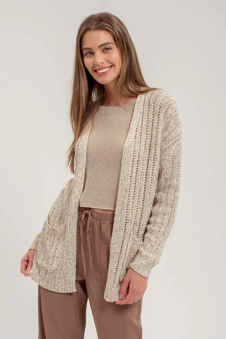 Beige crochet knit cardigan over light top and brown pants for a stylish look