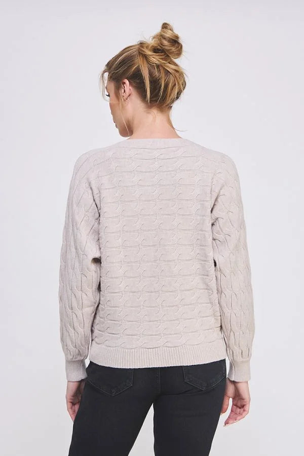 Beige long sleeve cable knit sweater worn by a person with blonde hair in a bun