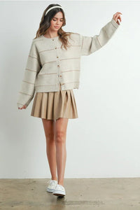 Beige pleated skirt with white sneakers and button front striped cardigan from shop daisy
