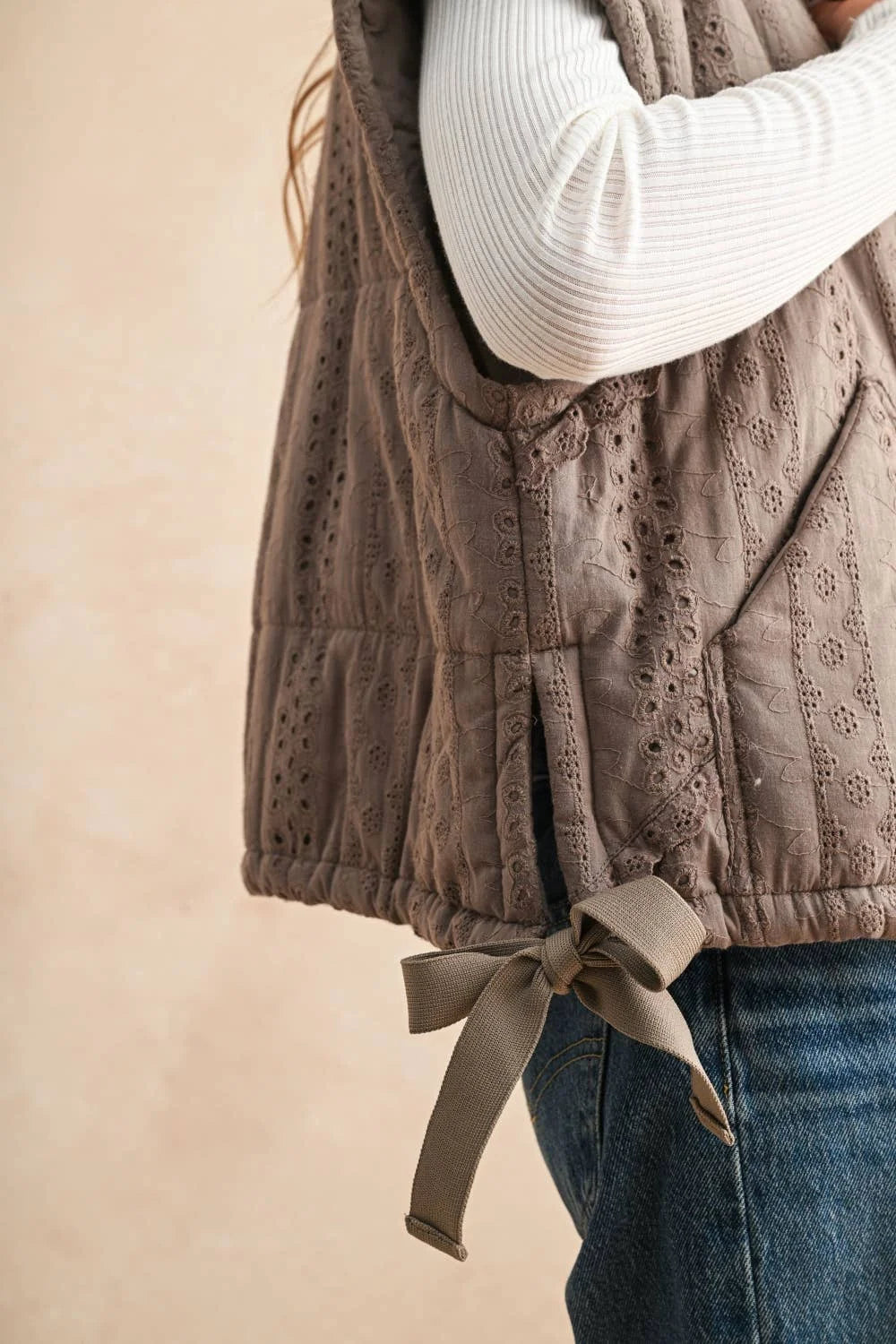 Beige quilted eyelet vest with lace crochet trim and bow tie closure